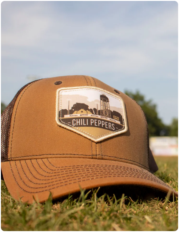 Brown and tan trucker hat featuring a landscape patch with a water tower, barn, and 'Chili Peppers' text displayed on grass