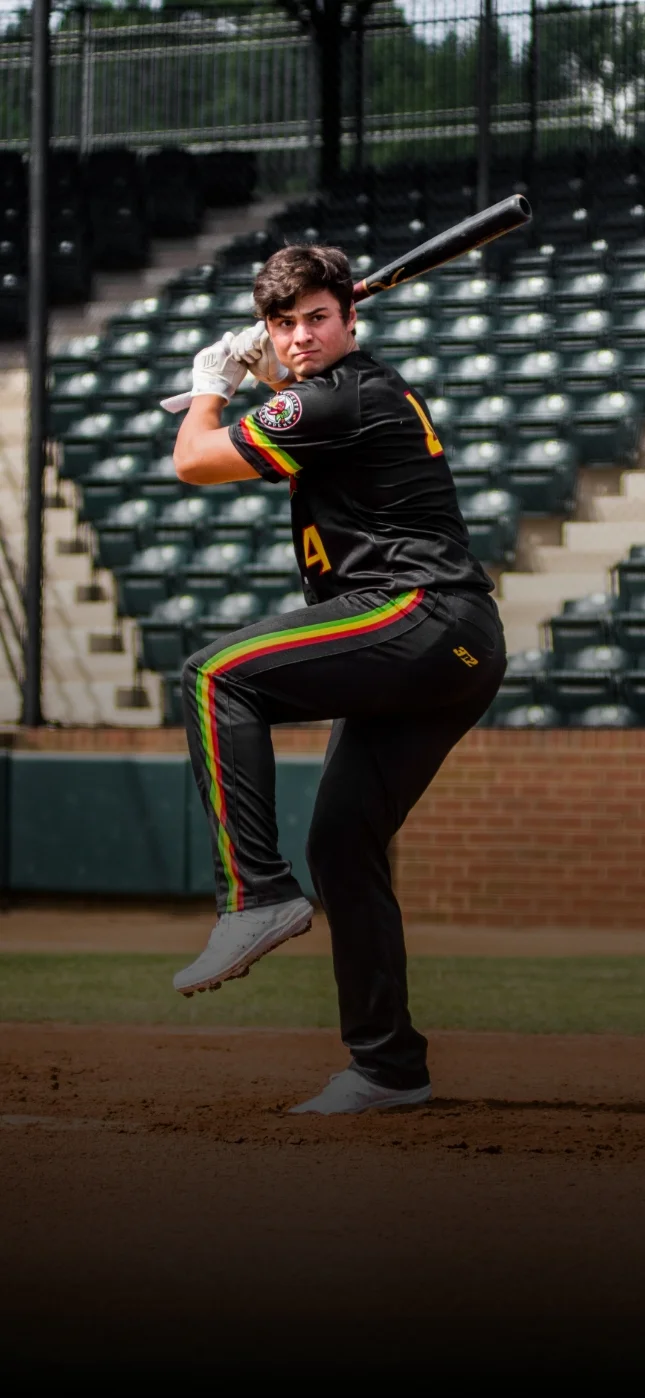 Chili Peppers player in a black uniform with red and green stripes winding up for a pitch at Shepherd Stadium.